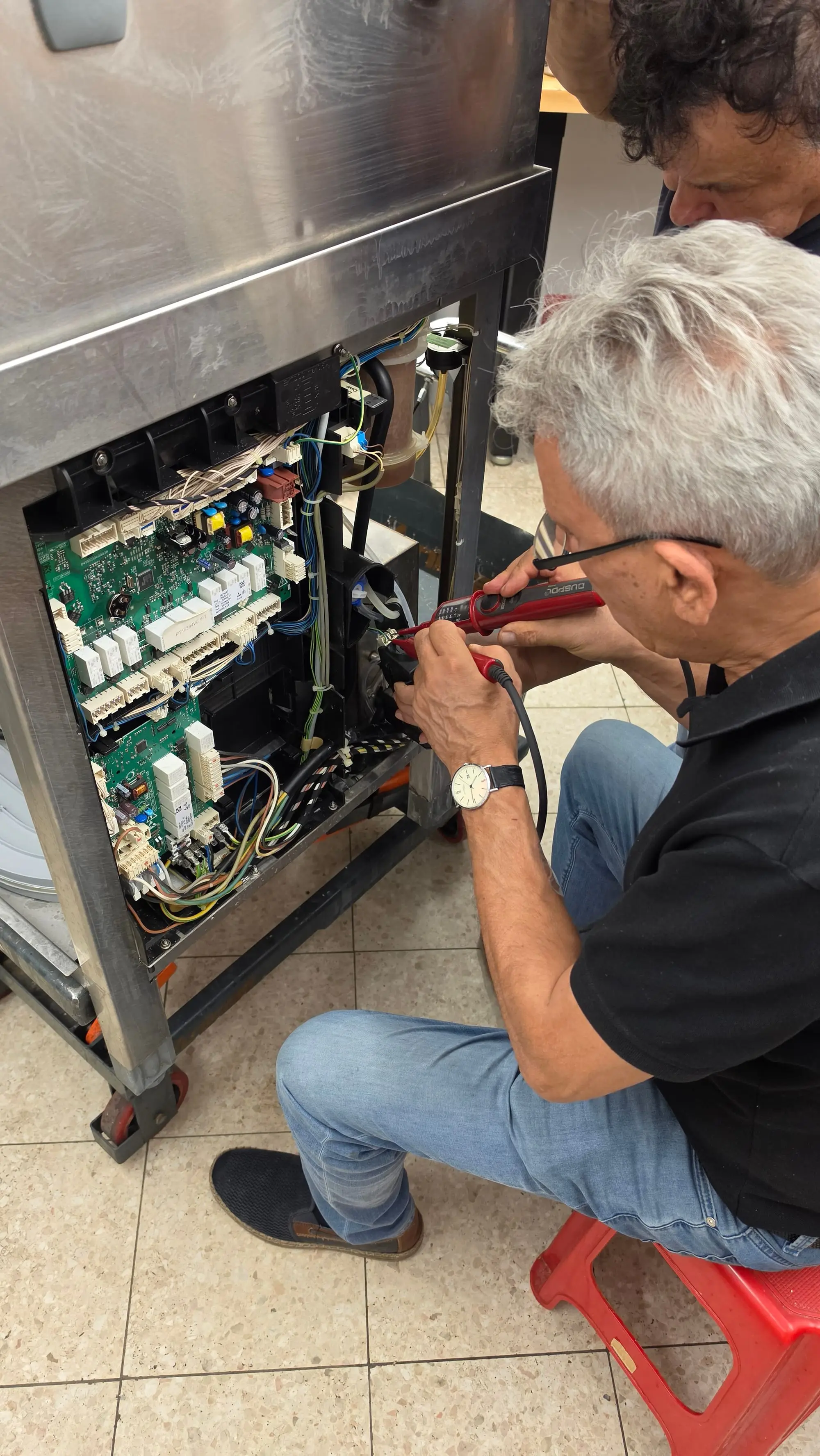 Techniker der Materazzi GmbH prüft mit dem Spannungsprüfer die Elektronik eines geöffneten Gastrogeräts